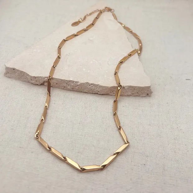 Gold necklace on a textured beige surface