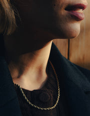 Close-up of a person wearing Gold Rope Twist Chain Necklace, with a blurred background