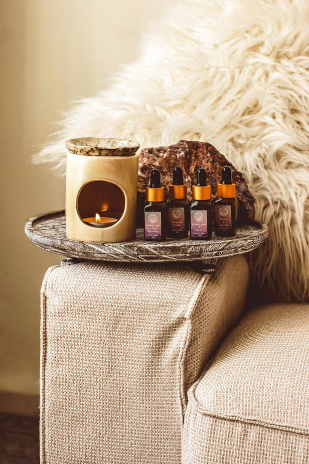 Trail of essential oil bottles on a tray with a lit candle on a textured surface