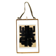 Abstract black artwork in a gold frame on a white background
