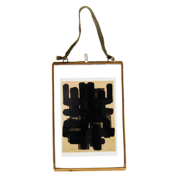 Abstract black artwork in a gold frame on a white background