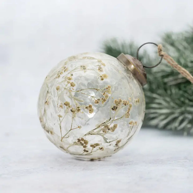 Decorative glass ball ornament with dried flowers on a white background