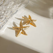 Gold starfish earrings on a white surface 