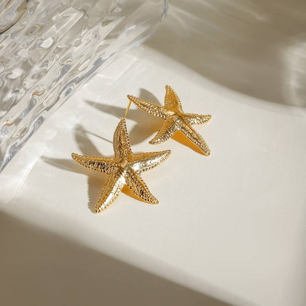 Gold starfish earrings on a white surface 
