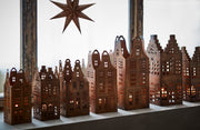Decorative wooden cityscape with lit windows and a star above on a white background