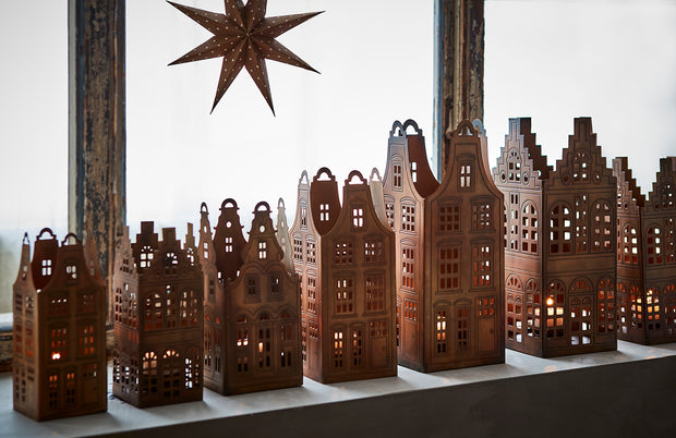 Decorative wooden cityscape with lit windows and a star above on a white background