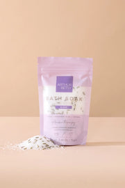 Purple package of bath soak with white text on a beige background