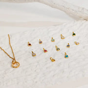 Gold necklace with small pendant options on a textured white surface