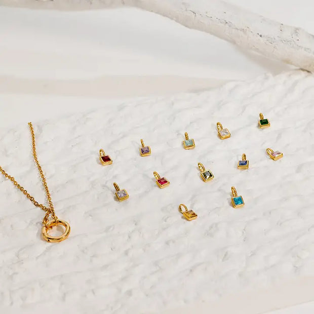 Gold necklace with small pendant options on a textured white surface