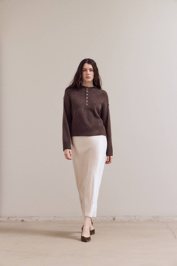 Woman wearing Button Detail Sweater in Chestnut  white pants against a plain background