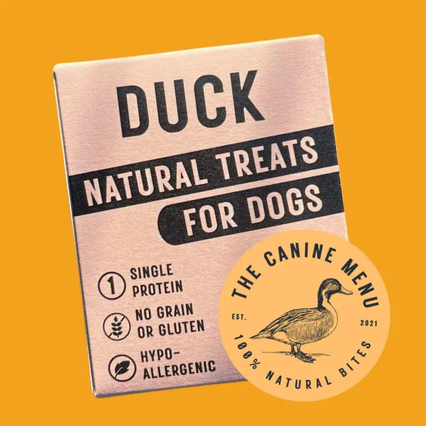 Box of duck natural treats for dogs with 'The Canine Menu' branding on a yellow background