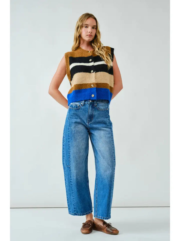 Woman wearing a colorful sleeveless top and blue jeans against a white background