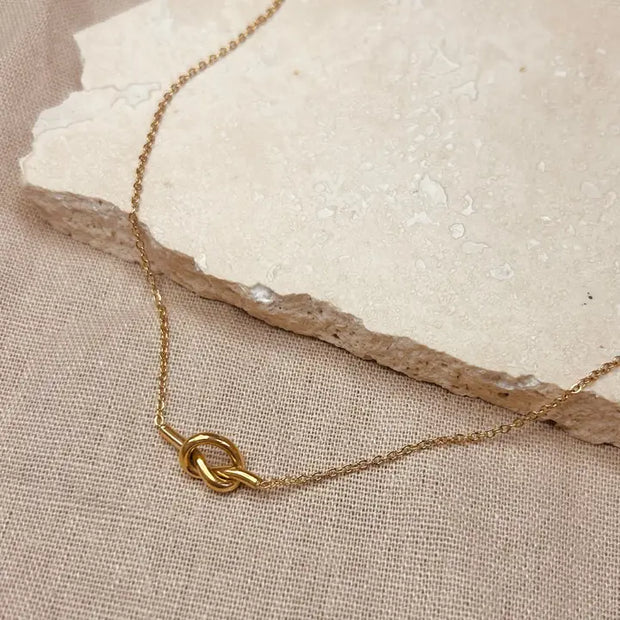 A delicate gold chain necklace with a knot detail. Little Nell Jewellery