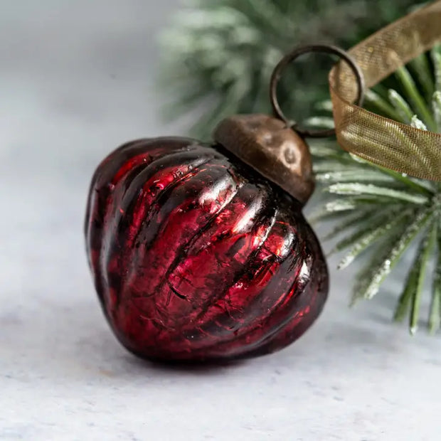Red glass ornament with a brown top on a light background
