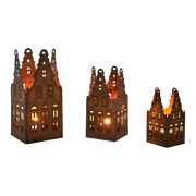 Three decorative lanterns shaped like houses with lit interiors on a white background