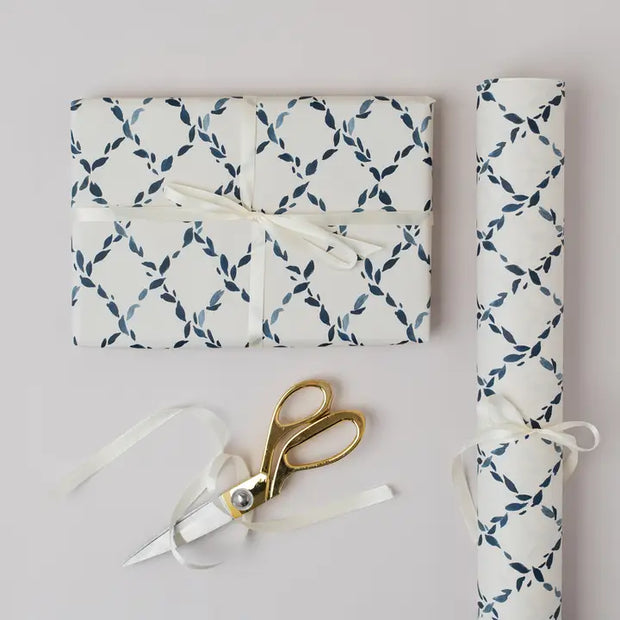 Gift wrapped in blue and white patterned paper with a gold scissors on a light gray background