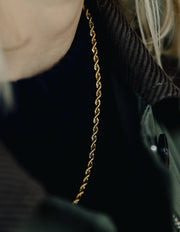 Close-up of Gold Rope Twist Chain Necklace, worn by a person with a blurred background