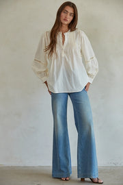 Model wearing Woven Cotton Long Sleeve Button Up Round Neck Top in cream