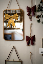 Decorative wall mirror with gold bow and red bows hanging on a wall - From Victoria Shop