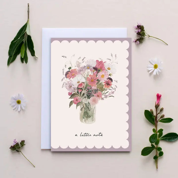 Greeting card with floral design and 'a little note' text, surrounded by flowers and leaves on a light background