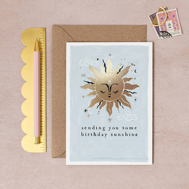 Greeting card with sun illustration and text, pen, and stamps on a beige background
