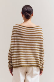 Person wearing a striped sweater and white pants against a plain background