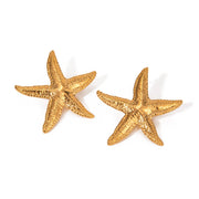 Gold starfish earrings on a white background