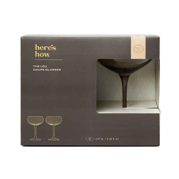 Box of 'The Lou Coupe Glasses' by 'here's how' with a glass visible through the window.