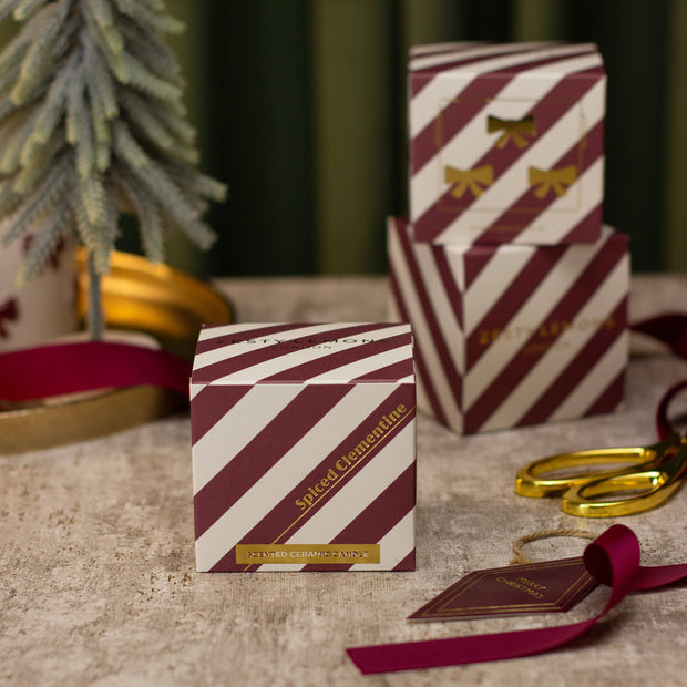Red and white striped gift box with 'Sliced Clementine' text on a textured surface with decorative elements.