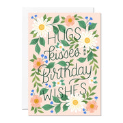 Fabulously floral, the caption on this female “Hugs, Kisses, Birthday Wishes” with handwritten lettering, surrounded by lush foliage, blooming flowers and forest green leaves all on a neutral background.