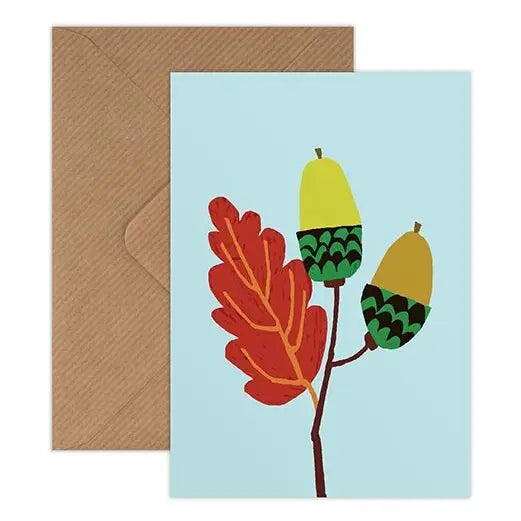 Greeting card with colorful acorn design on a light blue background, accompanied by a brown envelope.
