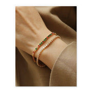 Close-up of a wrist wearing two beaded bracelets on a beige background