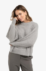 Woman wearing a gray sweater and pants on a white background