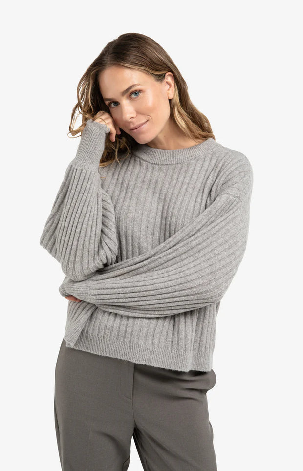 Woman wearing a gray sweater and pants on a white background