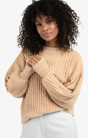 Woman wearing a beige sweater against a white background