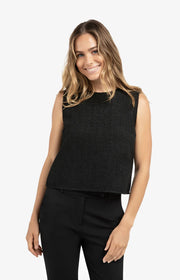 Woman wearing a black sleeveless top and black pants on a white background