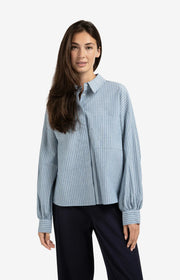 Woman wearing a light blue striped shirt and dark pants on a white background