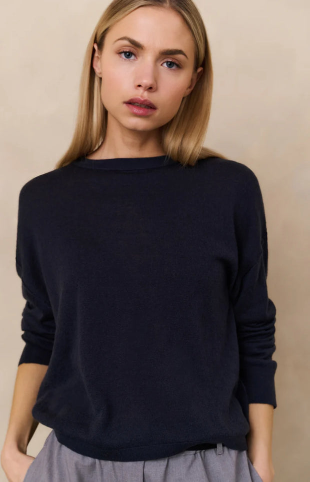 Woman wearing a navy sweater against a beige background
