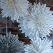 spiky layered paper star christmas decorations layered against a brick wall backdrop